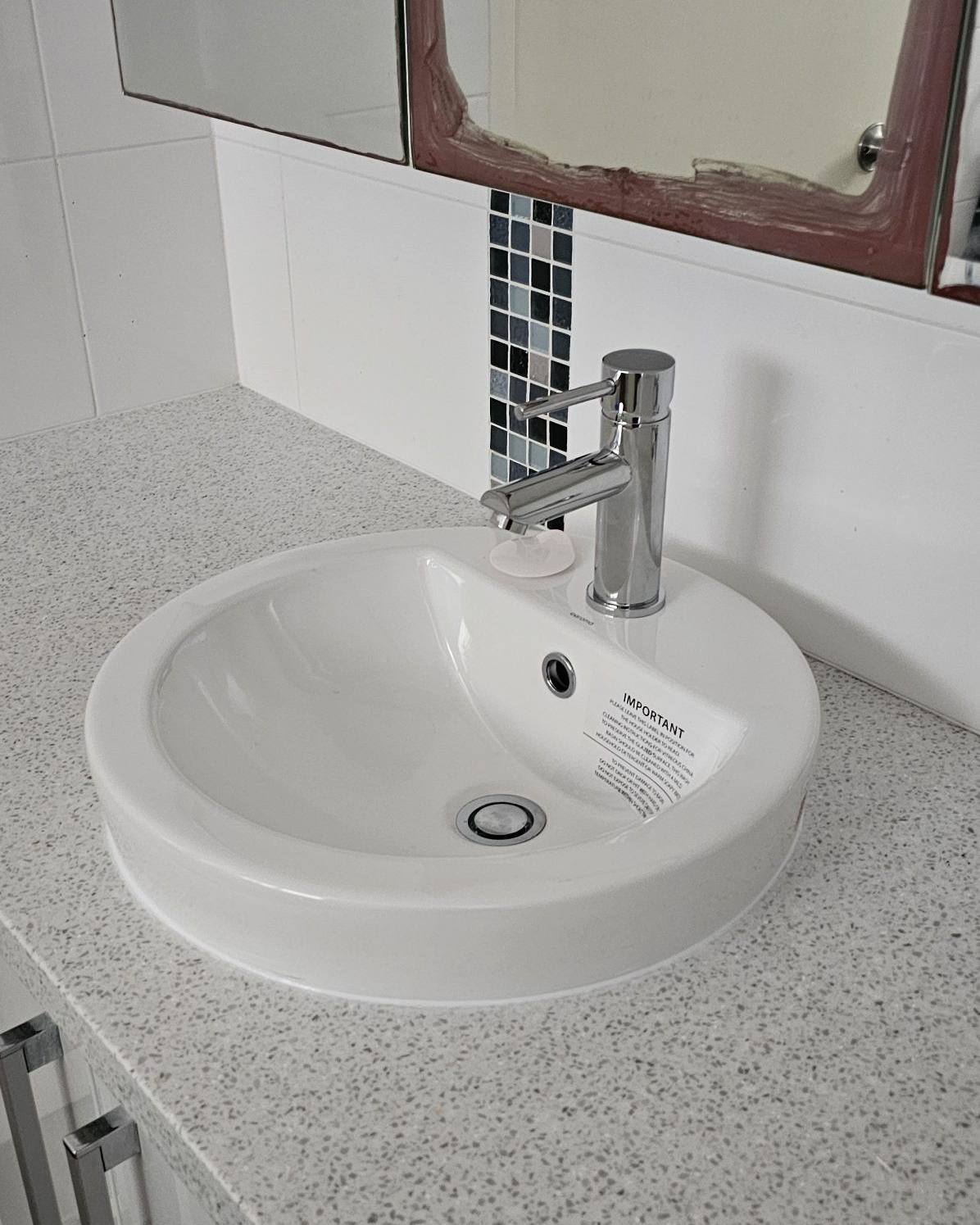 A replaced bathroom basin and mixer tap on a stone vanity
