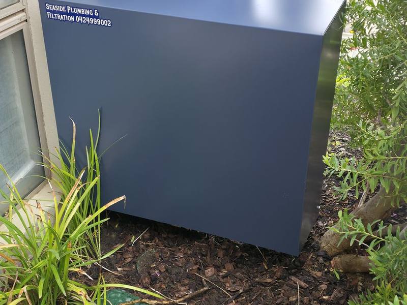 A blue-grey filter cover against a rendered wall among garden plants