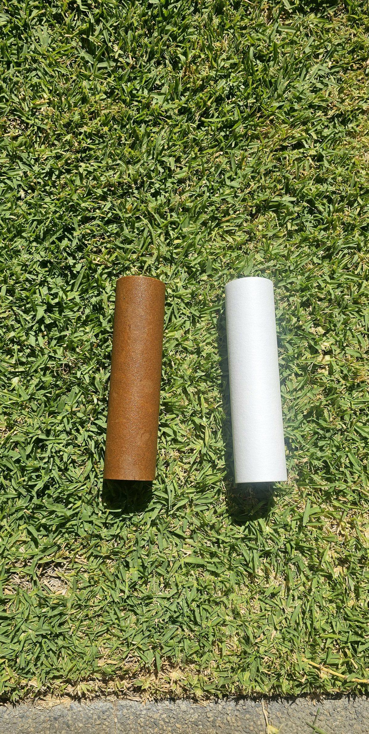A used brown filter cartridge beside a new white one on the lawn