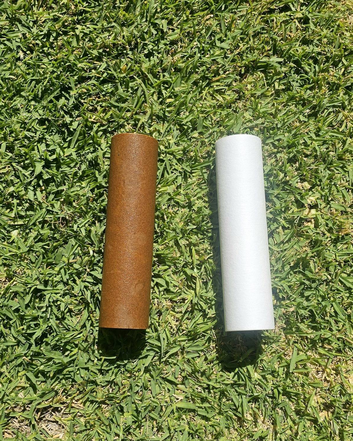 A used brown filter cartridge beside a new white one on the lawn