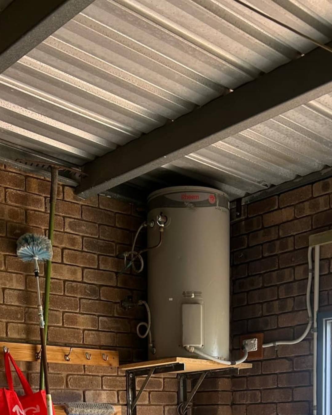 An old electric storage hot water unit in a carport, due for an upgrade
